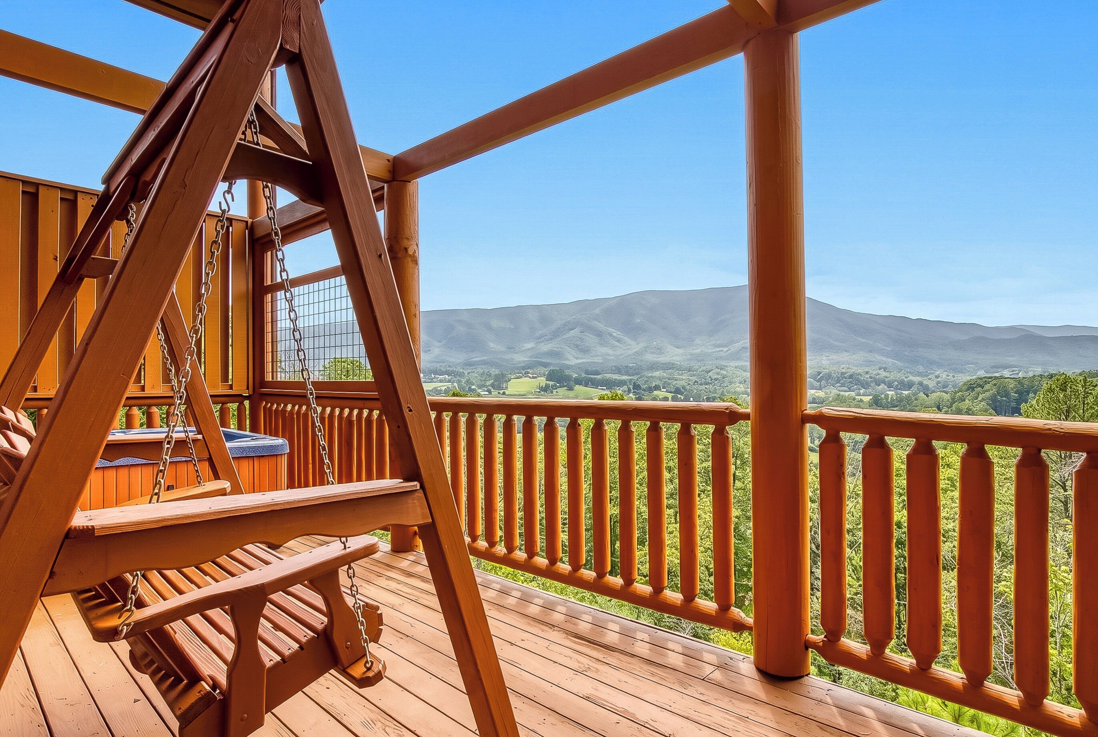 A wooden deck with a swing set and a view of rolling hills.