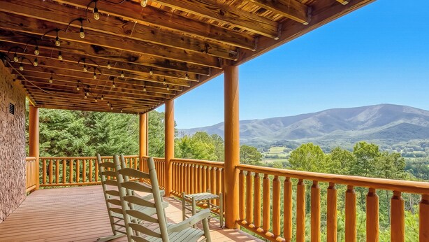 Eine Holzterrasse mit Bergblick, einem Stuhl und einem Tisch.