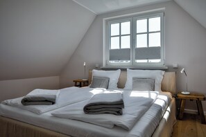Une chambre à coucher avec un grand lit, deux tables de chevet, une fenêtre et un plafond en pente.