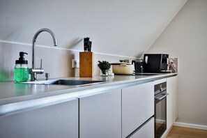 A modern kitchen with a built-in dishwasher, a sink, and a coffee machine. - Experience the ultimate vacation at Haus am Meer Strandburg on Sylt (Wenningstedt-Braderup (Sylt))