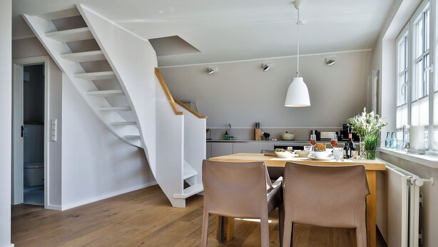 Een moderne keuken met een houten eettafel, twee stoelen en een hanglamp.