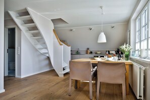 A modern kitchen with a wooden dining table, two chairs, and a pendant light. - Experience the ultimate vacation at Haus am Meer Strandburg on Sylt (Wenningstedt-Braderup (Sylt))