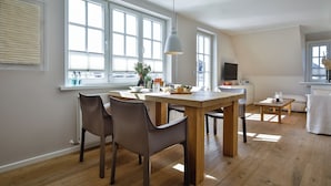 Een moderne keuken met een eethoek, grote ramen en een houten tafel.