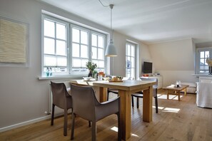 A modern kitchen with a dining area, large windows, and a wooden table. - Experience the ultimate vacation at Haus am Meer Strandburg on Sylt (Wenningstedt-Braderup (Sylt))