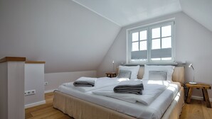 Een slaapkamer met een groot bed, een raam, een nachtkastje en een bedtafel.