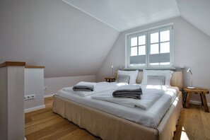 A bedroom with a large bed, a window, a bedside table, and a nightstand. - Experience the ultimate vacation at Haus am Meer Strandburg on Sylt (Wenningstedt-Braderup (Sylt))
