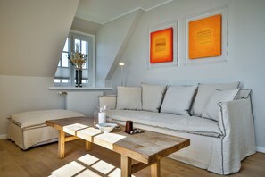 A cozy living room with a wooden coffee table, a sofa, and a window with a view. - Experience the ultimate vacation at Haus am Meer Strandburg on Sylt (Wenningstedt-Braderup (Sylt))