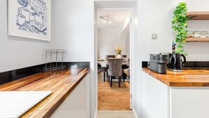 A modern kitchen with a wooden countertop, a coffee machine, and a hanging plant. - Etihad & Co-op Live, 3-Bed, Free Parking (Droylsden)