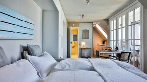 Ein modernes Hotelzimmer mit einem großen Bett, einem Schreibtisch mit Stuhl und Blick durch große Fenster.