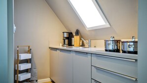 Eine moderne Küche mit Oberlicht, Edelstahlgeräten und einem Holzregal.