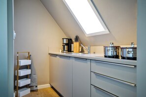 Eine moderne Küche mit Oberlicht, Edelstahlgeräten und einem Holzregal.