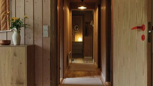 A wooden hallway with a door on the right, a light fixture above, and a plant on the left. - Holiday home with terraces near Udsholt Strand (Udsholt)