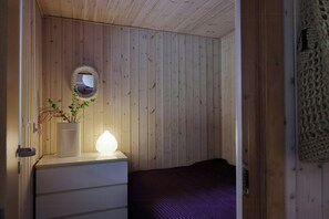 A wooden-paneled room with a bed, a dresser, a mirror, and a wall-mounted light fixture. - Holiday home with terraces near Udsholt Strand (Udsholt)
