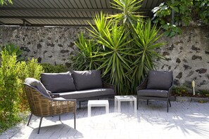 A patio with a sofa, two chairs, and a small table.