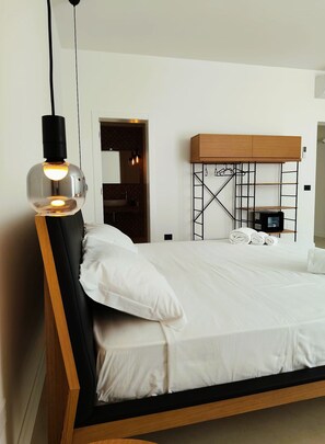 A bed with a wooden frame, a hanging light fixture, and a wall-mounted TV. - HOTEL PIETRA NERA (Catania)
