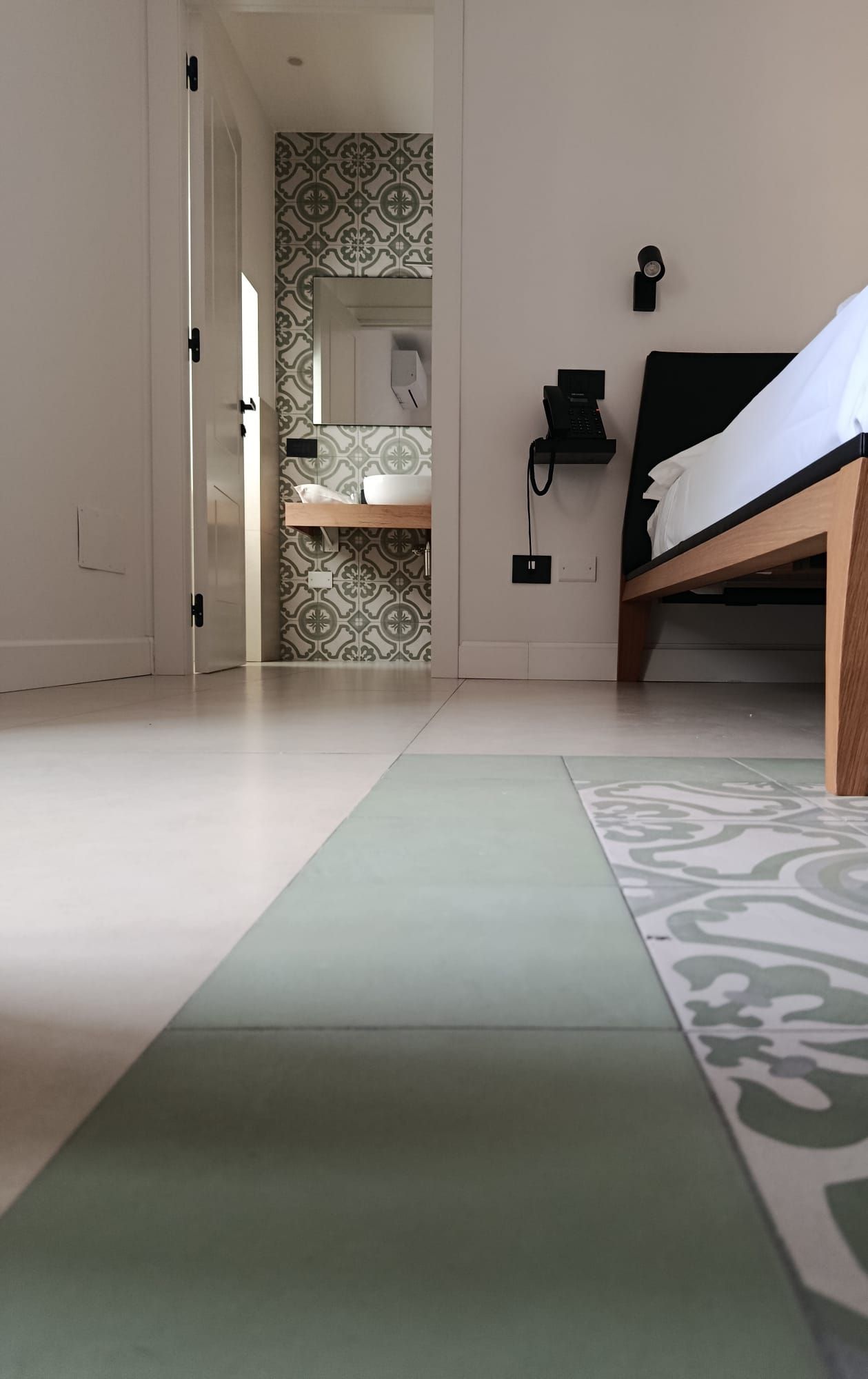 Een slaapkamer met een bed, een bedtafeltelefoon en een badkamer zichtbaar door een open deur.