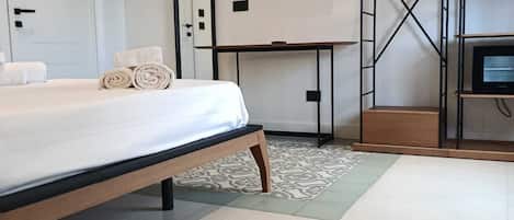 A hotel room with a bed, a desk, a television, and a wardrobe.