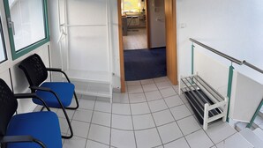 Ein Zimmer mit blauem Sessel, weißer Bank und Blick auf eine Küche und einen Balkon.