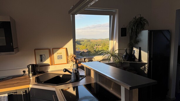 Eine moderne Küche mit Einbauherd, Spüle und Fenster mit Blick auf eine schöne Landschaft.