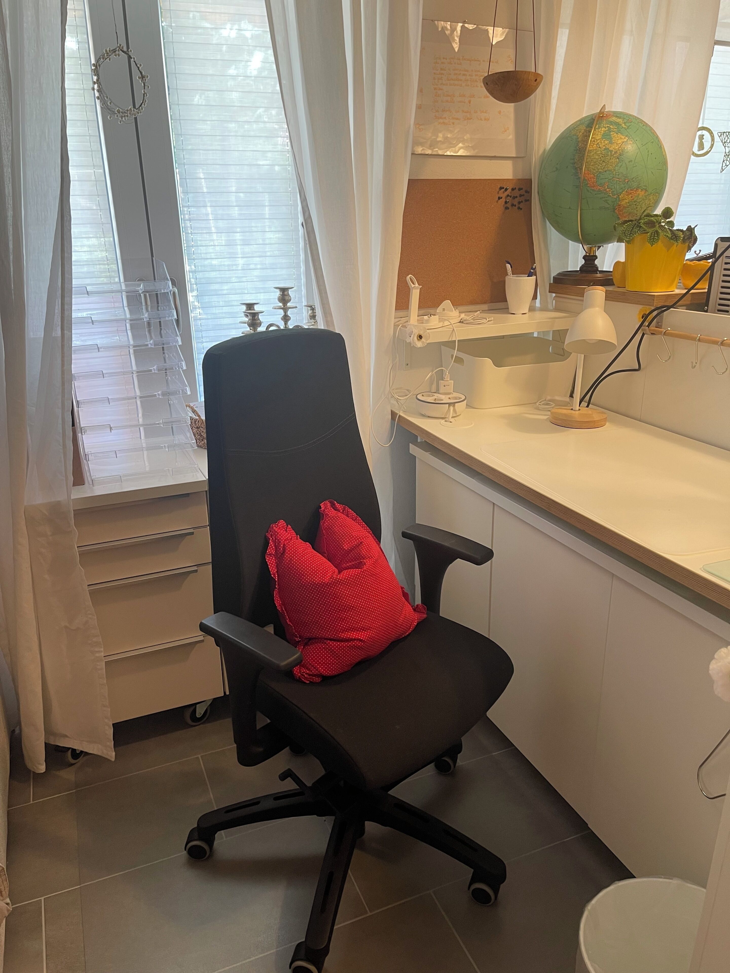 Ein Zimmer mit Schreibtisch, Stuhl, Globus und einem Fenster mit Jalousien.