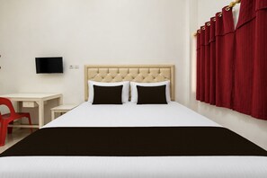 Una habitación de hotel con una cama, un escritorio, una silla y un televisor en la pared.