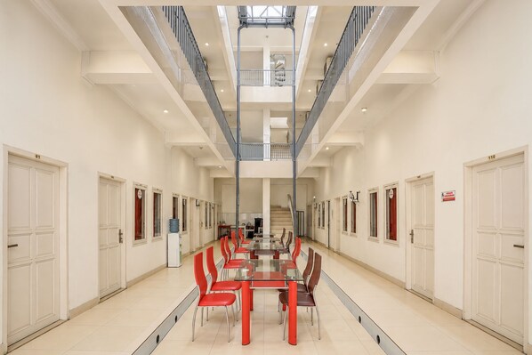 A spacious indoor area with a central table and chairs, a staircase, and multiple doors. - Hotel O Wisma Fortuner (Makassar)
