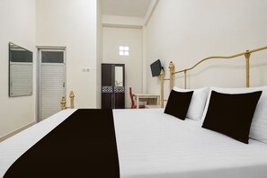 A hotel room with a bed, a desk, a chair, a wardrobe, and a television. - Hotel O Wisma Fortuner (Makassar)