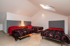 A room with two beds, a skylight, and a nightstand with a lamp.