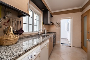 A kitchen with a granite countertop, stainless steel sink, and a range hood.