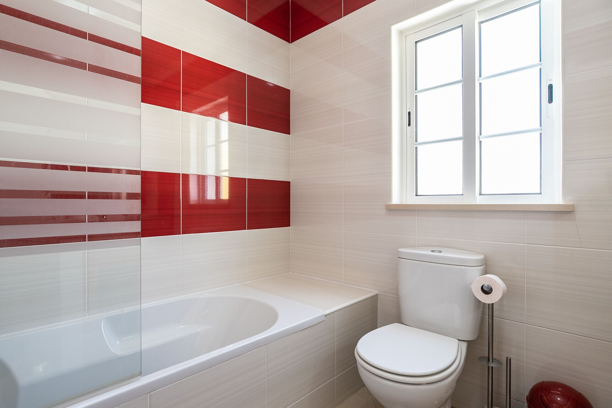 Un baño con bañera, inodoro y ventana.