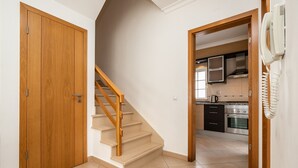 A staircase leading to a kitchen area with a telephone on the wall.