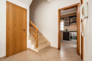 A staircase leading to a kitchen area with a telephone on the wall.