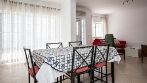 A dining area with a table set for four, chairs, a red sofa, and a green armchair.