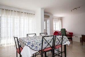 A dining area with a table set for four, chairs, a red sofa, and a green armchair.