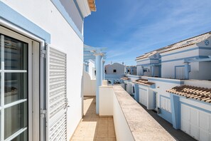A narrow alleyway with buildings on either side, featuring a clear sky and a tiled roof.