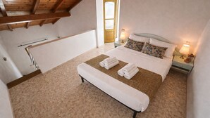 Ein Schlafzimmer mit einem Bett, zwei Nachttischlampen, einem Fenster und einer Tür.