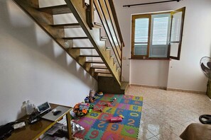A staircase leading to an upper floor, a window with blinds, and a play area with a colorful alphabet mat. - Our eco friendly home 2 min from Cabral Beach (Sal Rei)