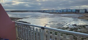 A coastal view with a sandy beach, a white fence, and buildings in the background. - Our eco friendly home 2 min from Cabral Beach (Sal Rei)