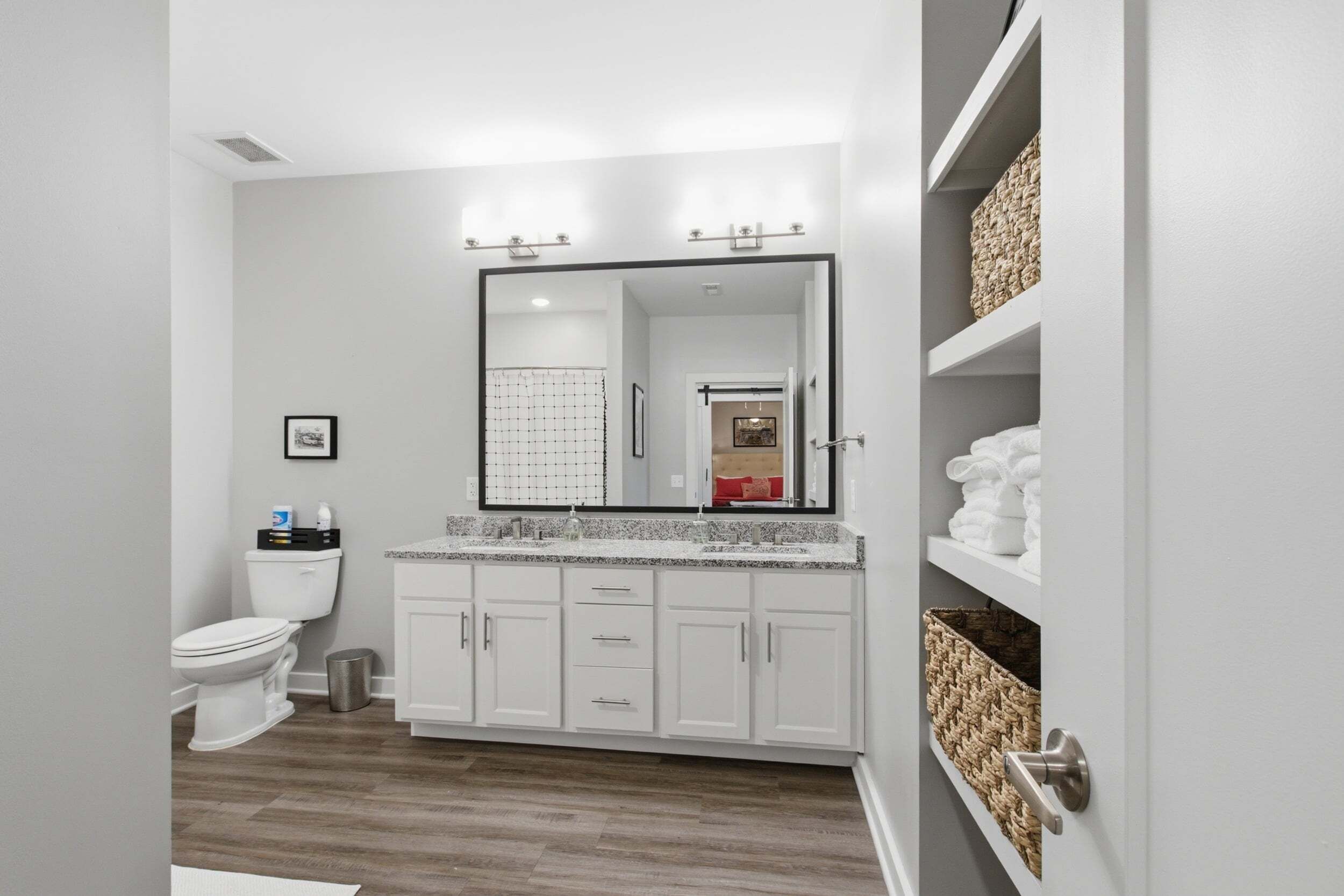 A modern bathroom with a white vanity, a large mirror, and a shower area.