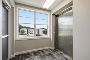 Ein Flur mit einem großen Fenster, einem Aufzug und einem Schachbrettmuster-Teppich.