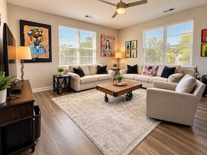 A living room with a sectional sofa, a coffee table, and artwork on the walls.