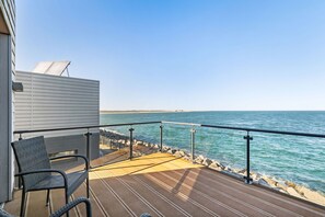 Eine Terrasse mit Stuhl und einem kleinen Gebäude mit Blick auf ein Gewässer.
