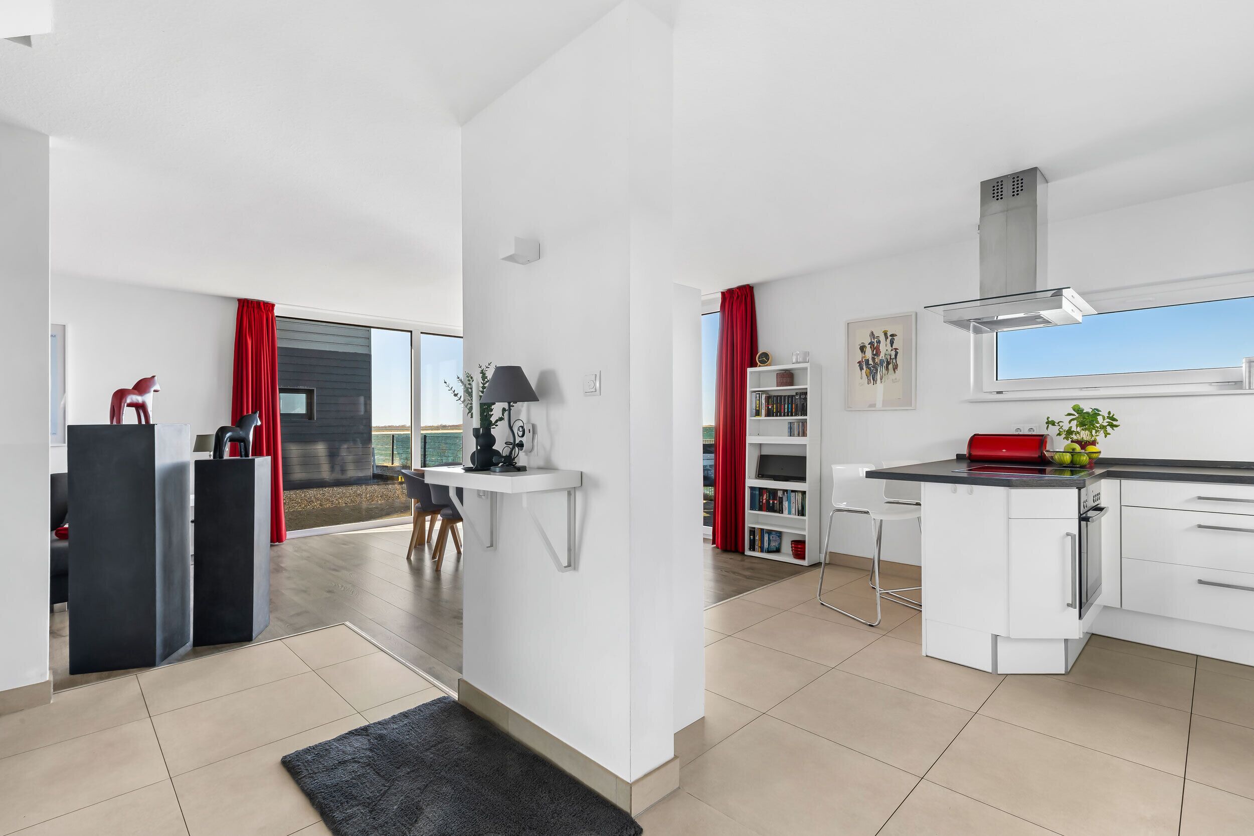 A modern kitchen with white cabinetry, a black countertop, and a red rug.