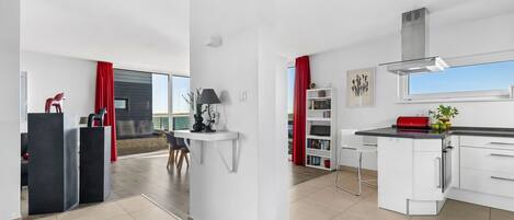 A modern kitchen with white cabinetry, a black countertop, and a red rug.