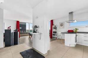 Une cuisine moderne avec des meubles blancs, un plan de travail noir et un tapis rouge.