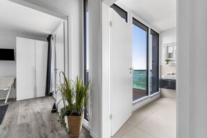 A modern interior with a large sliding glass door leading to a balcony with a view of the sea. - Maritimes & Sea – Vacation Home with Sauna and Ocean View on the Beach (Olpenitz)