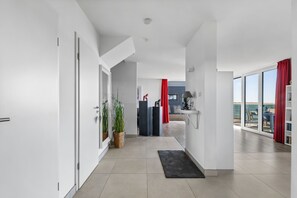 A modern interior with a hallway leading to a balcony with a view. - Maritimes & Sea – Vacation Home with Sauna and Ocean View on the Beach (Olpenitz)