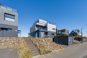 Ein modernes Wohngebäude mit einer Steinmauer, einer Treppe und blauem Himmel.