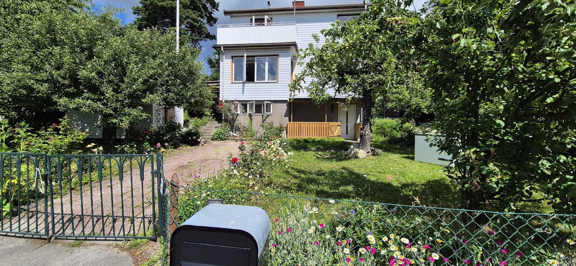 Un immobile residenziale con cancello, cassetta postale e un giardino curato con diverse piante e fiori.