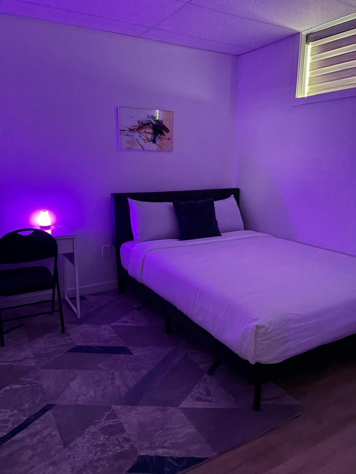 A bedroom with a bed, a desk, and a chair.